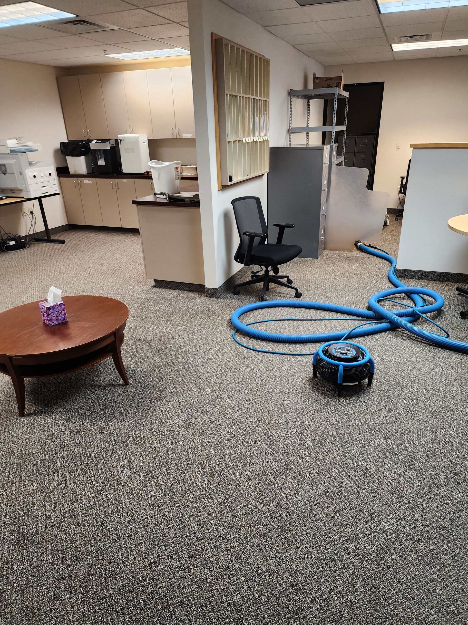 A room with a table and chairs and a vacuum cleaner on the floor.