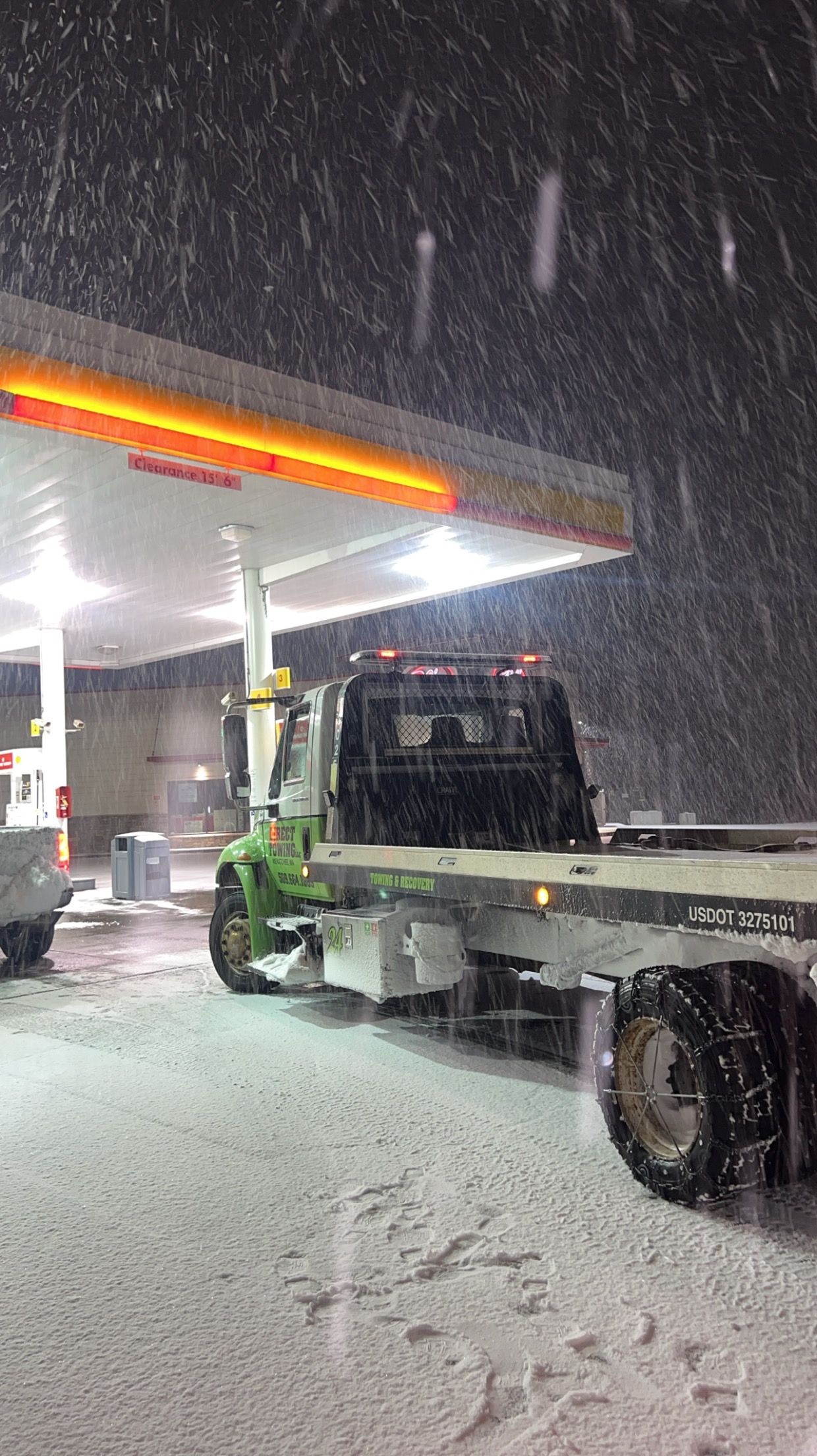 Tow truck at a gas station in heavy snowfall at night