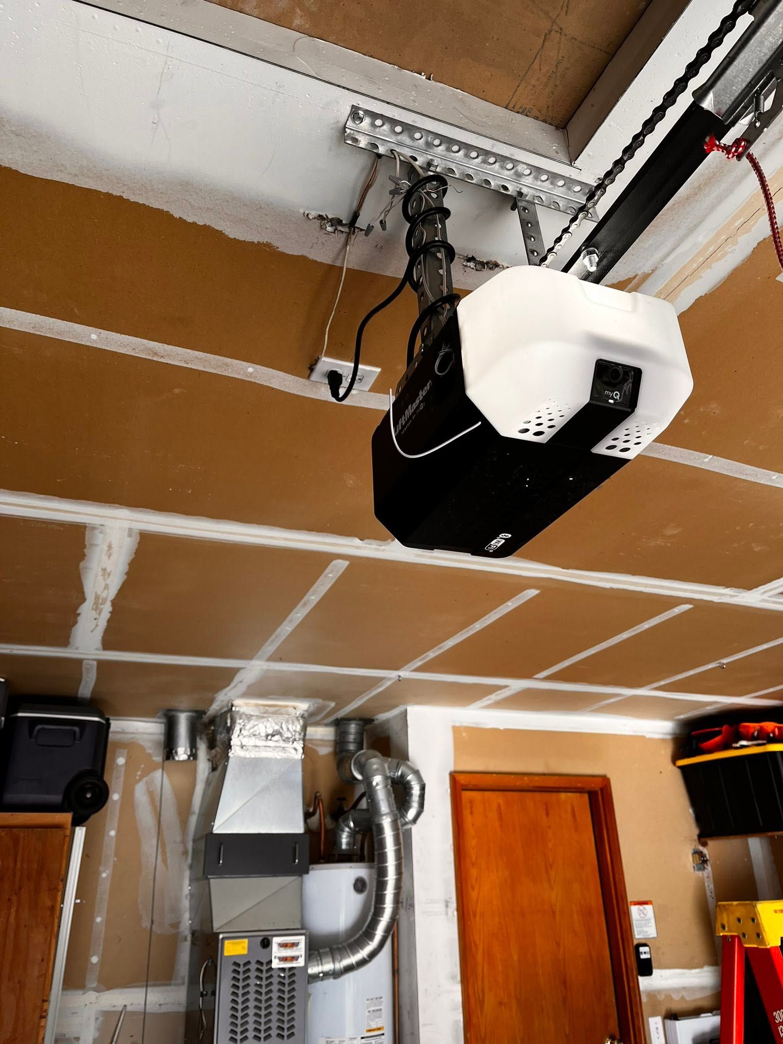 Garage ceiling with a suspended black-and-white garage door opener and hanging chains