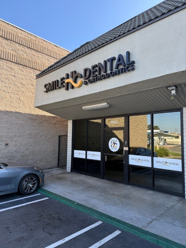 Smile Dental storefront with glass entrance, beige exterior, and parked car in front