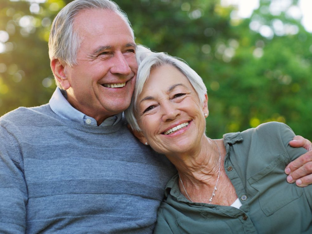 Smiling couple outdoors, embracing in a green park background
