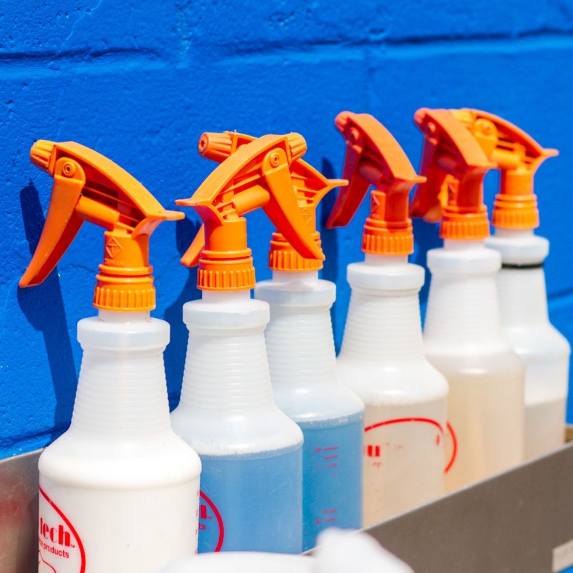 Car Wash Detail spray bottles lined up along a blue wall.
