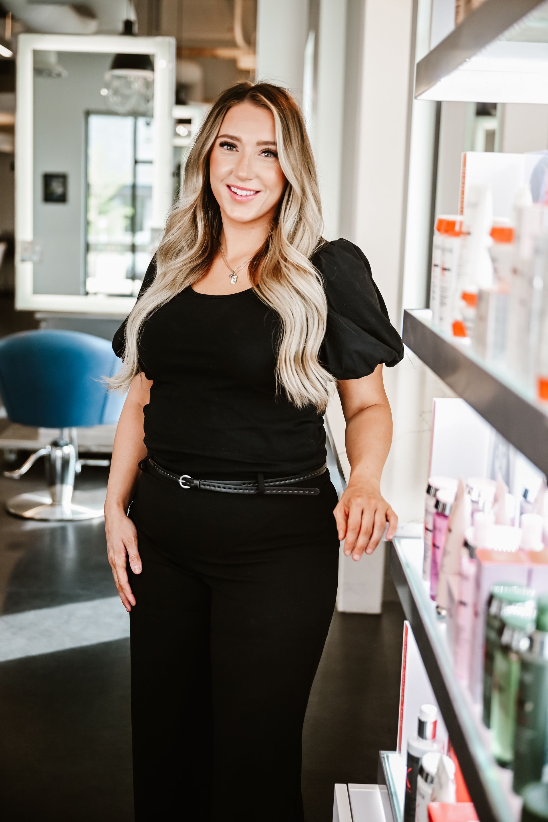 a woman with blonde hair is wearing a black shirt and smiling .