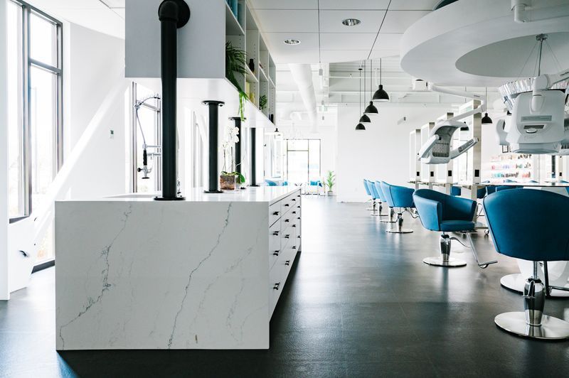 Modern bright hair salon interior with blue chairs, mirrors, and marble counters