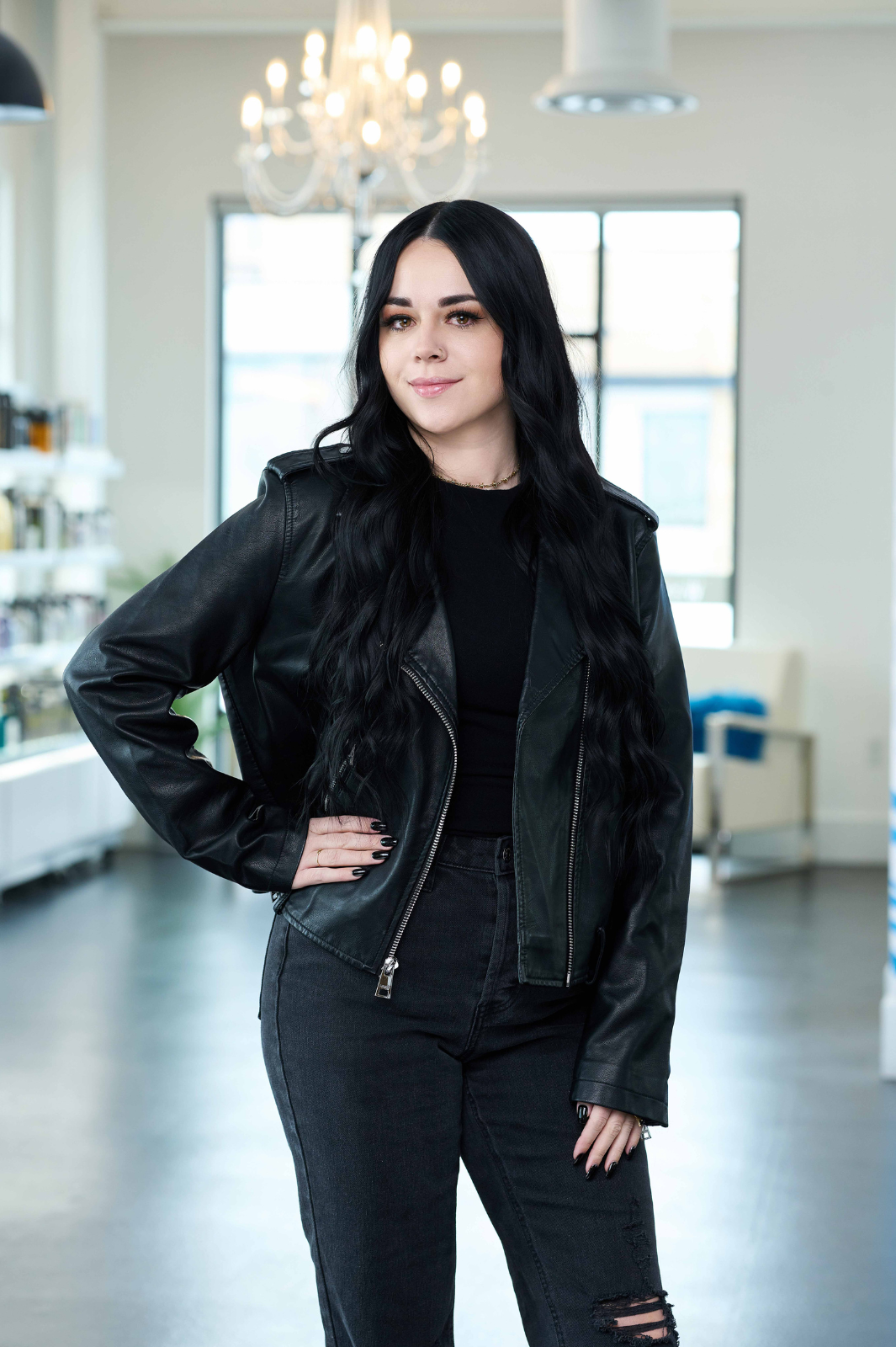 A woman wearing a black leather jacket and black jeans is standing in a room.