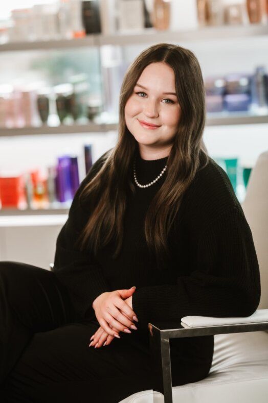 A woman is standing in front of a shelf full of hair products.
