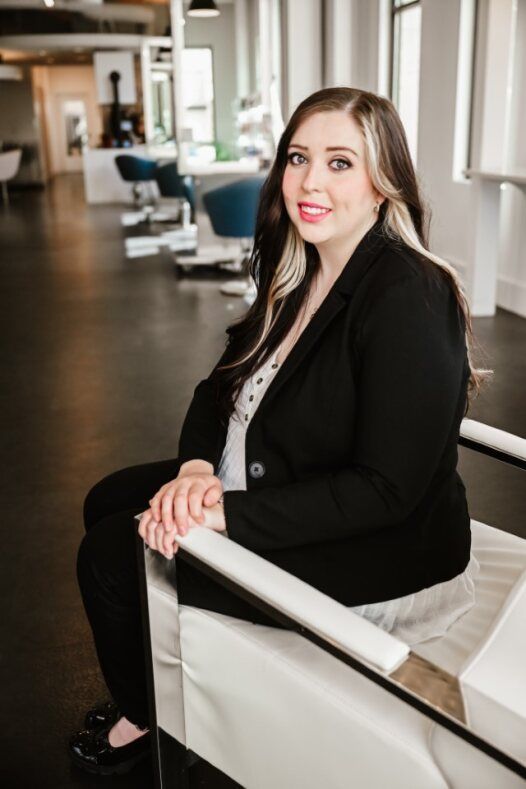 A woman in a black dress is sitting on a blue chair.