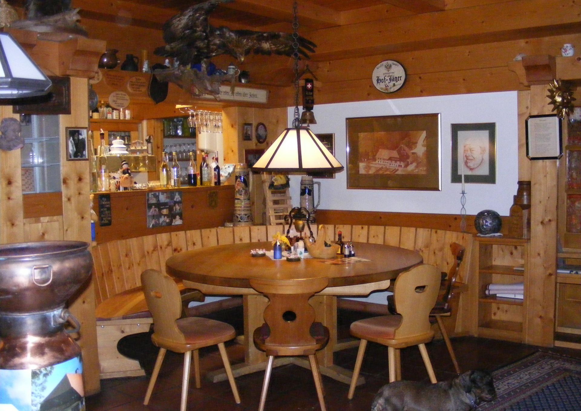 Gemütliches, holzgetäfeltes Esszimmer mit rundem Tisch, Stühlen und hängender Laterne