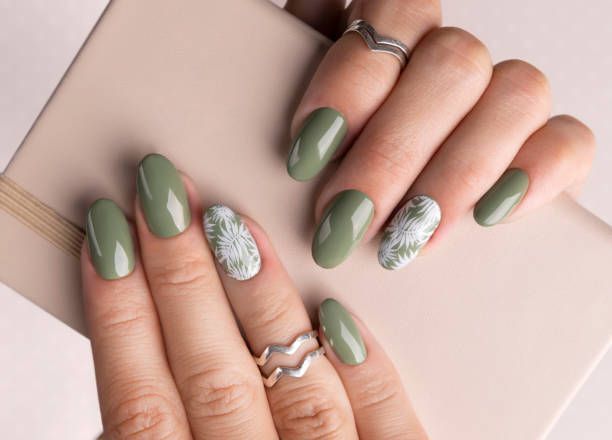 A close up of a woman's nails with green nail polish and rings.