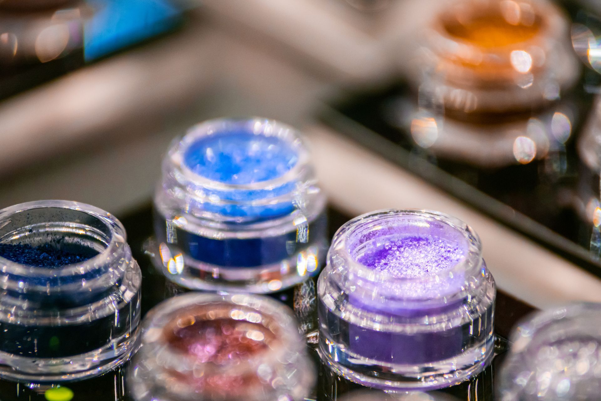 A bunch of jars of makeup are sitting on a table.