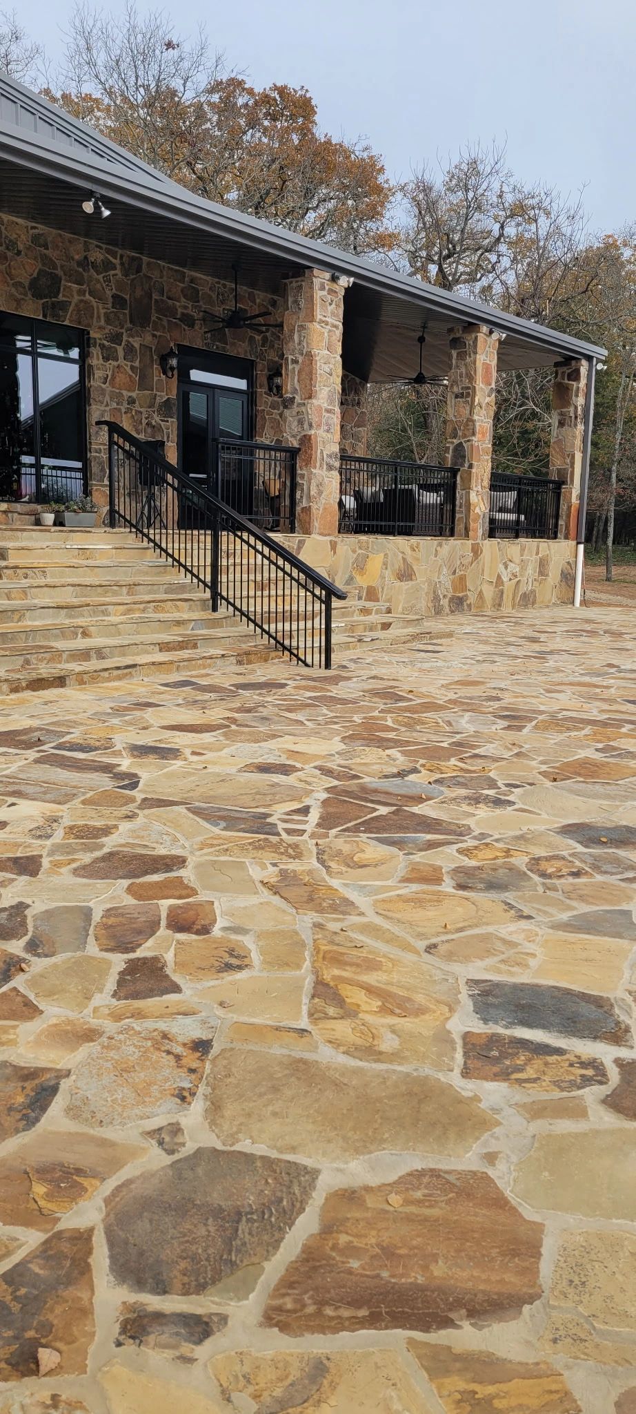 Stone-paved patio leading to a rustic building with columns and a ramp