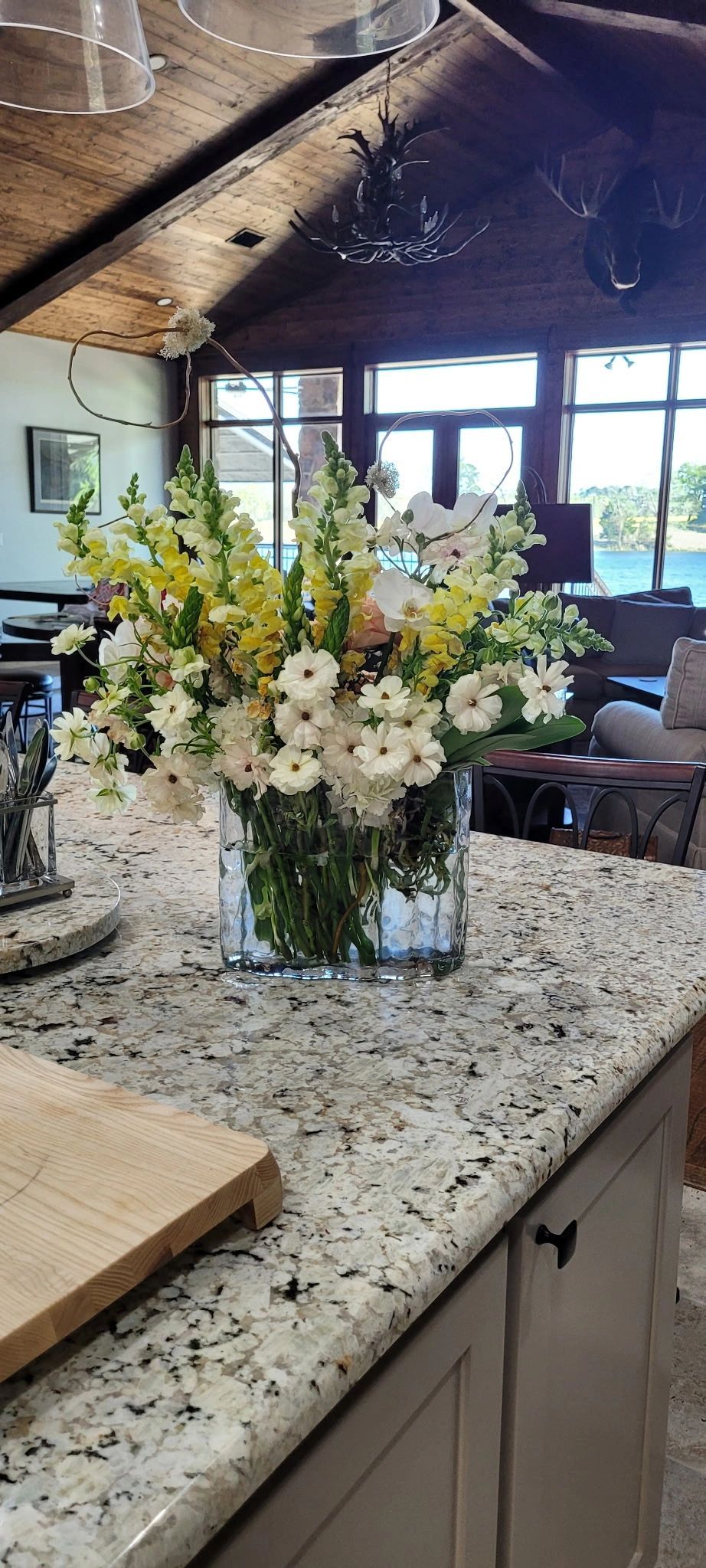 Kitchen island with a white flower arrangement in a granite countertop, overlooking a rustic living area