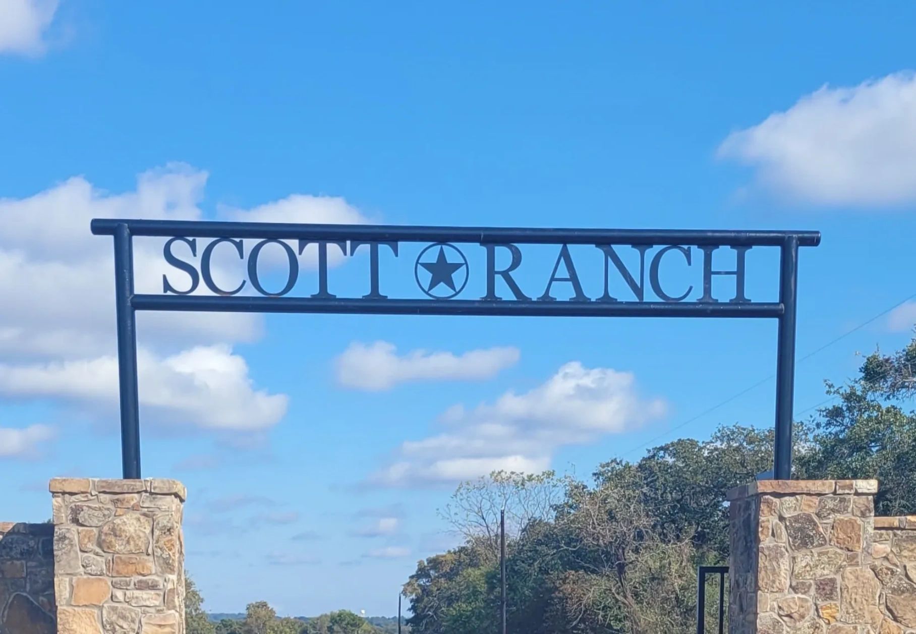 Entrance sign reading “Scotia Ranch” on a blue sky background with stone pillars