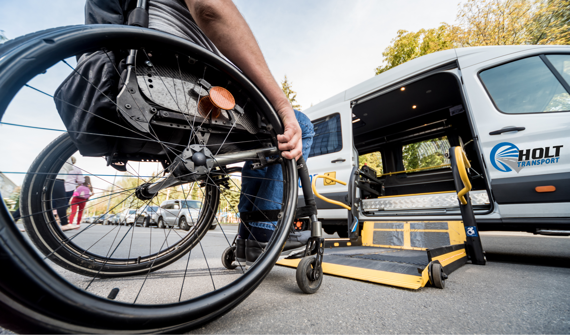 Person in wheelchair loading into a white accessible van with lowered ramp and wheelchair lift.