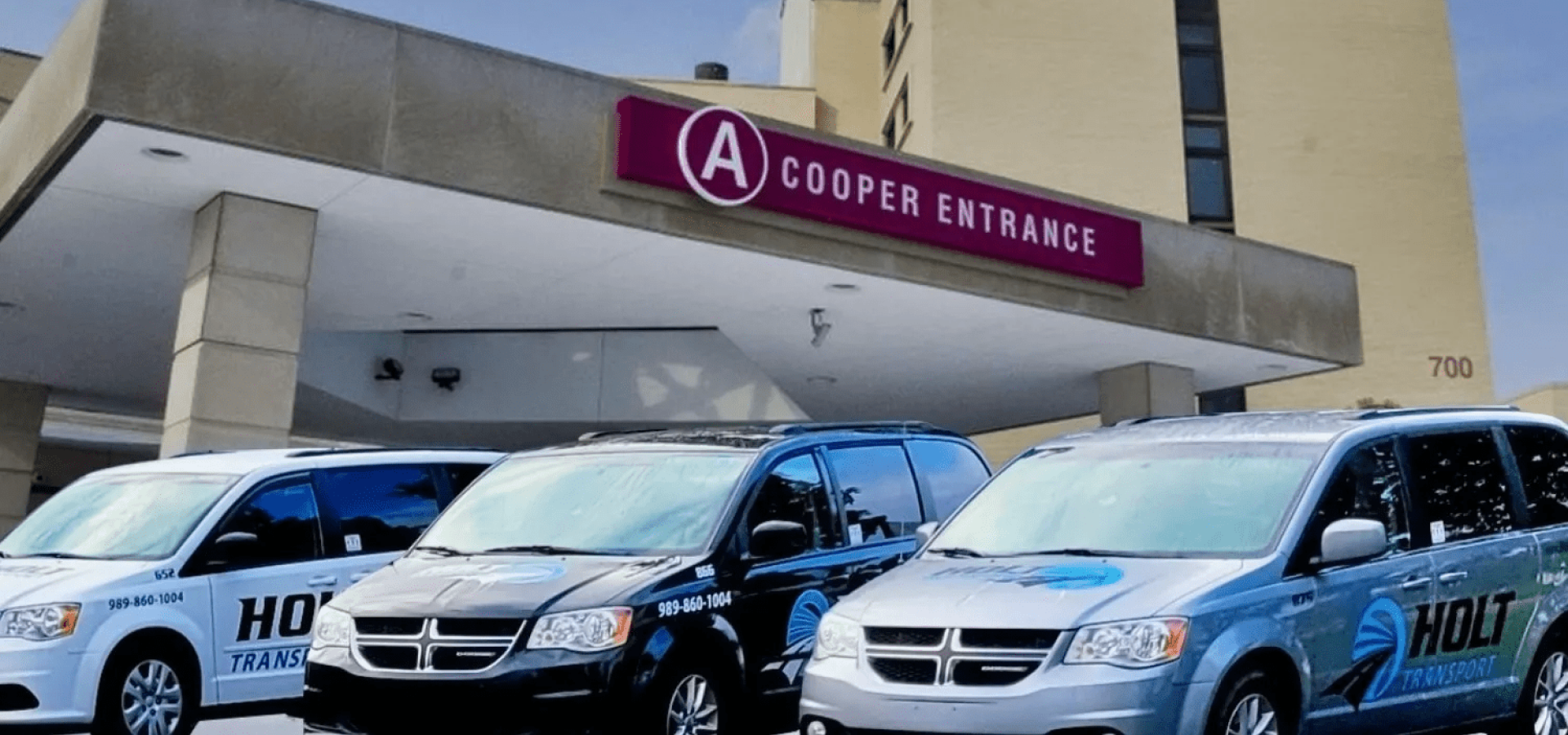 Blue and black cars parked outside a Cooper entrance with a pink sign above the door