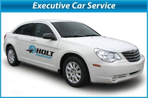 White sedan with “HOLT Transport” logo and “Executive Car Service” banner on blue background