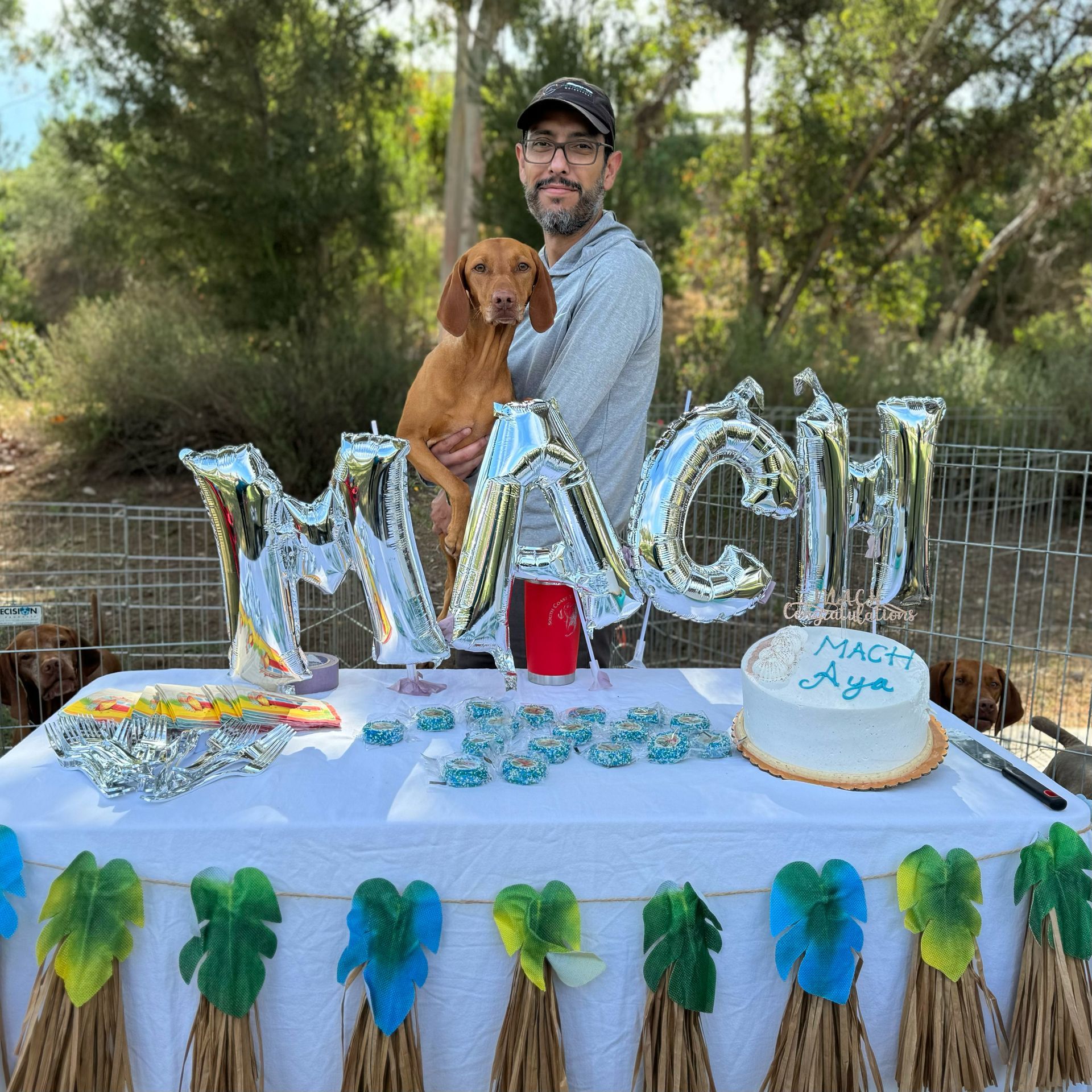 A man is holding a dog in front of a birthday table.