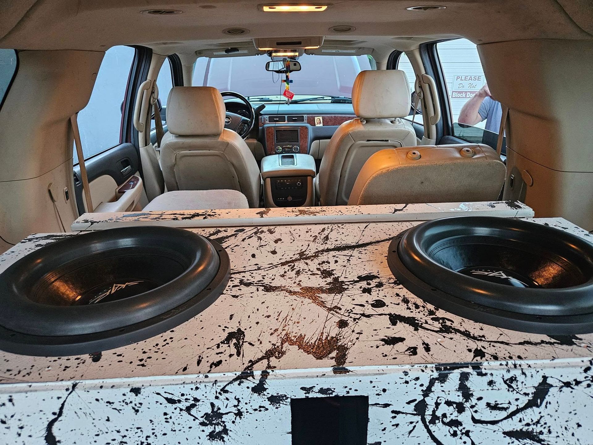 Car interior with a large custom speaker box filling the rear cargo area and seats visible ahead