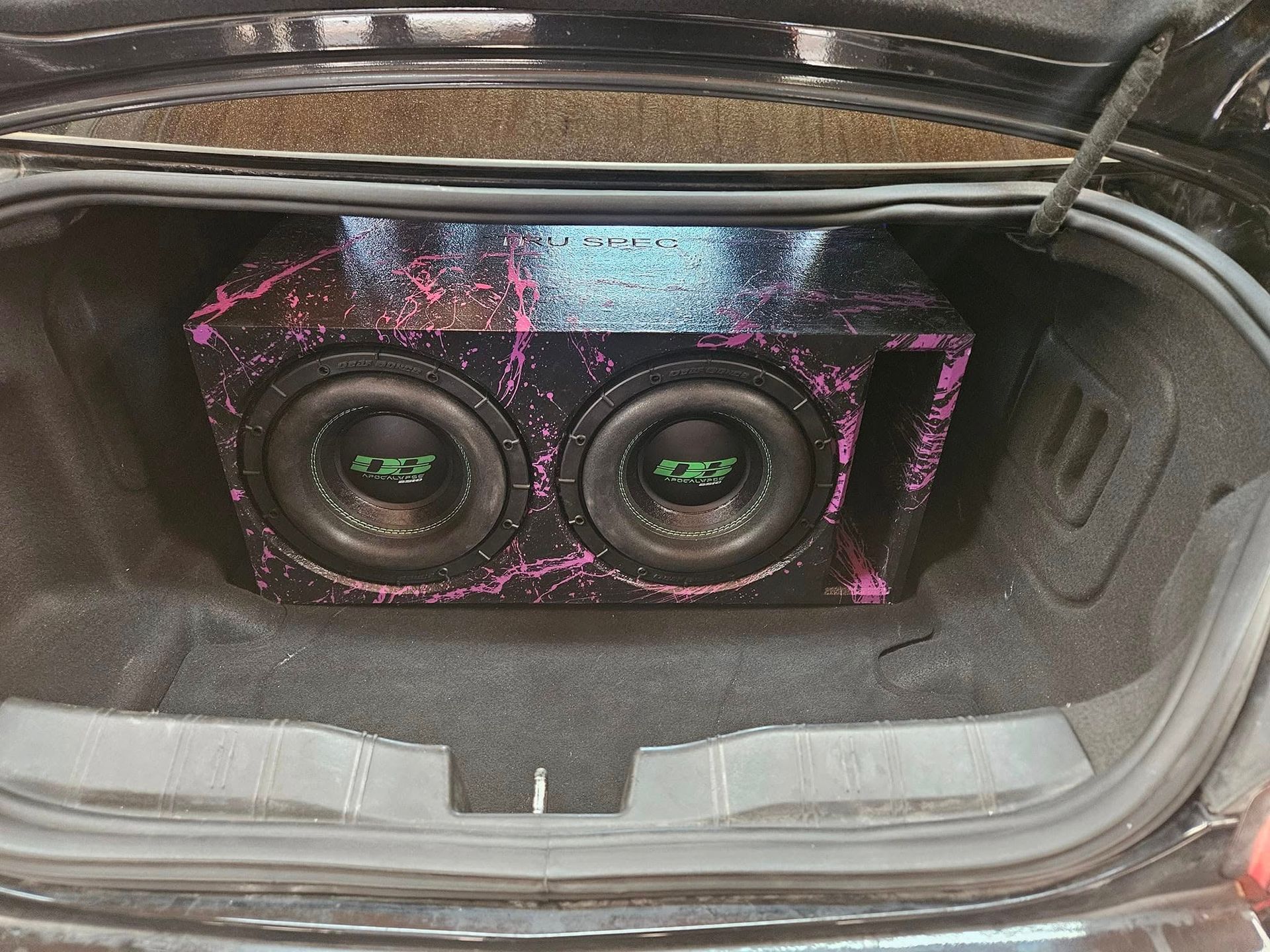 Custom purple-lit dual subwoofers installed in a car trunk
