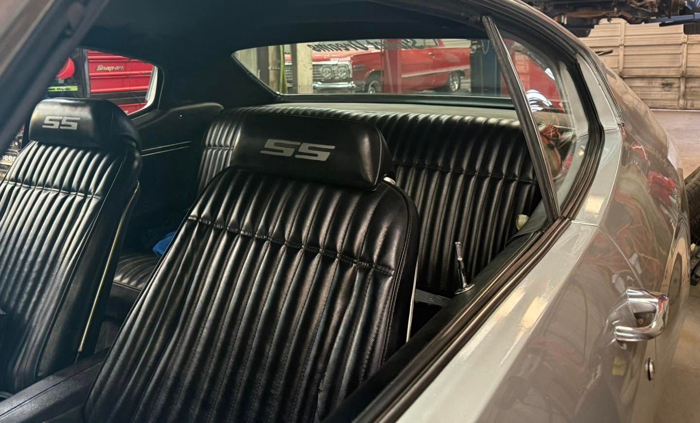 Black striped seats inside a classic car interior with chrome trim and rear bench seating