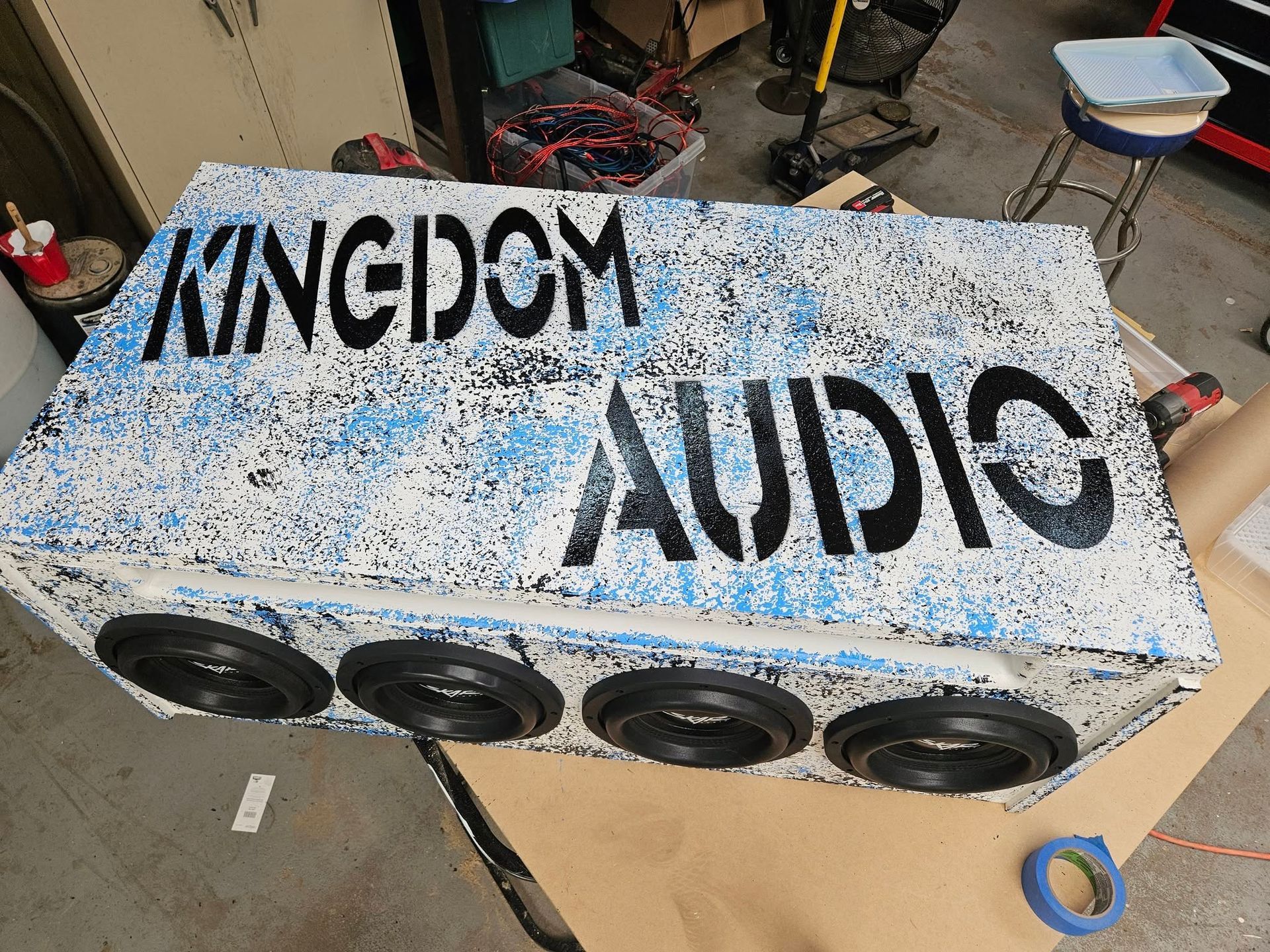 Speckled blue-and-white KINGDOM AUDIO speaker cabinet with four speakers in a workshop