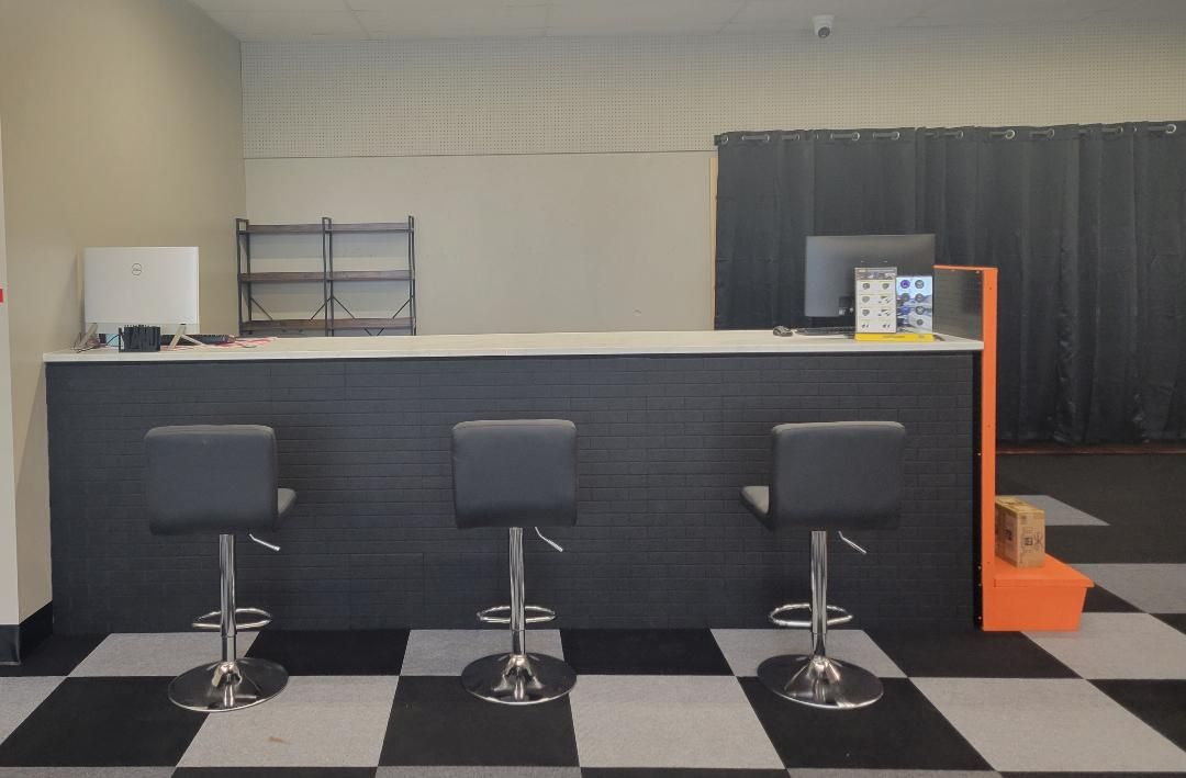 Office reception desk with three stools, black counter, and black-and-white checkered floor