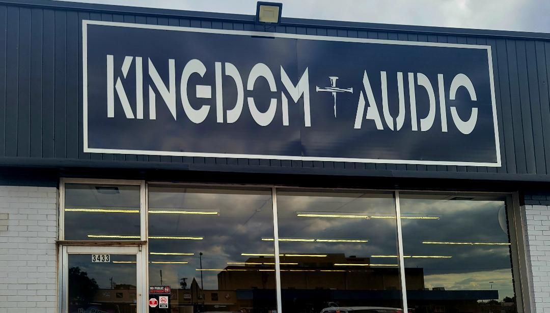 Storefront sign reading “KINGDOM AUDIO” above large windows