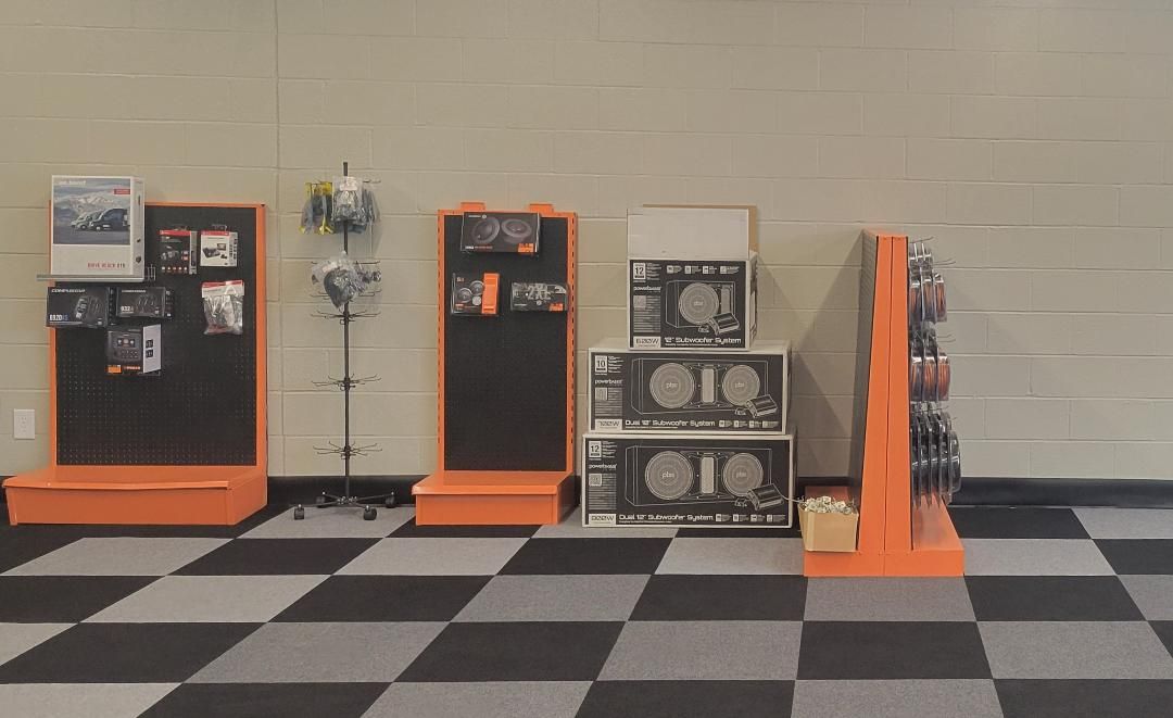 Orange-and-black product displays with stacked speakers and brochures in a store aisle