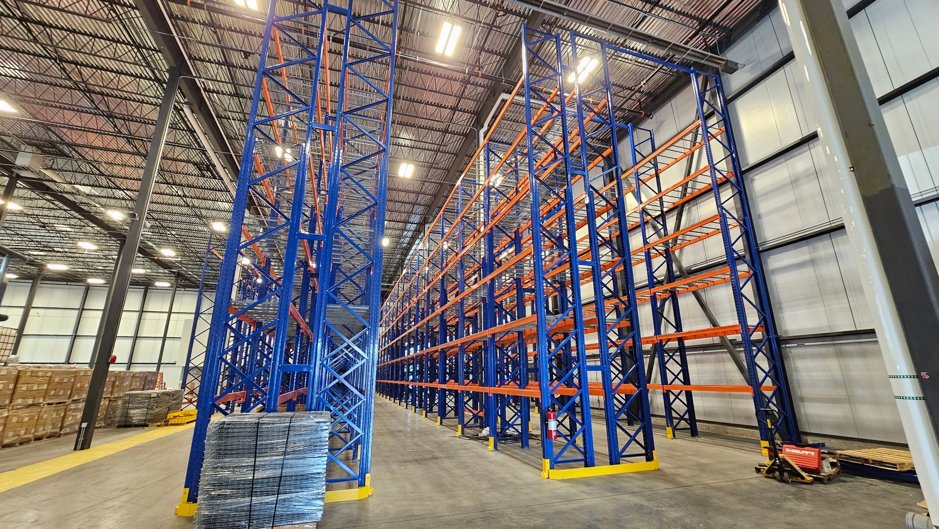 Industrial warehouse pallet racking installation with high-density storage racks and lift equipment in a commercial facility.