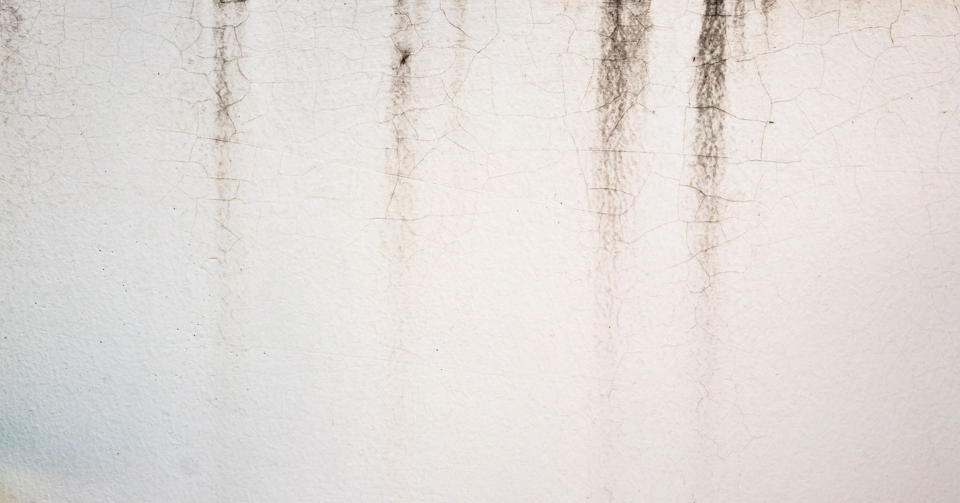 Water staining below a window on the stucco exterior of a commercial building.
