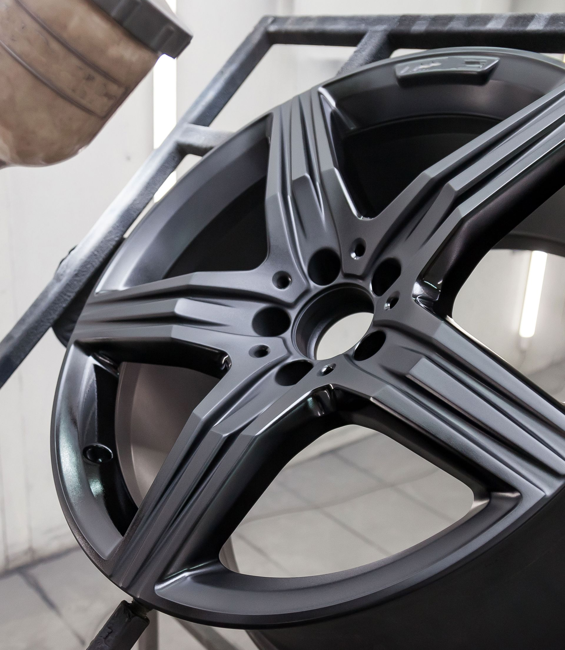 A car wheel being spray painted black in a workshop.