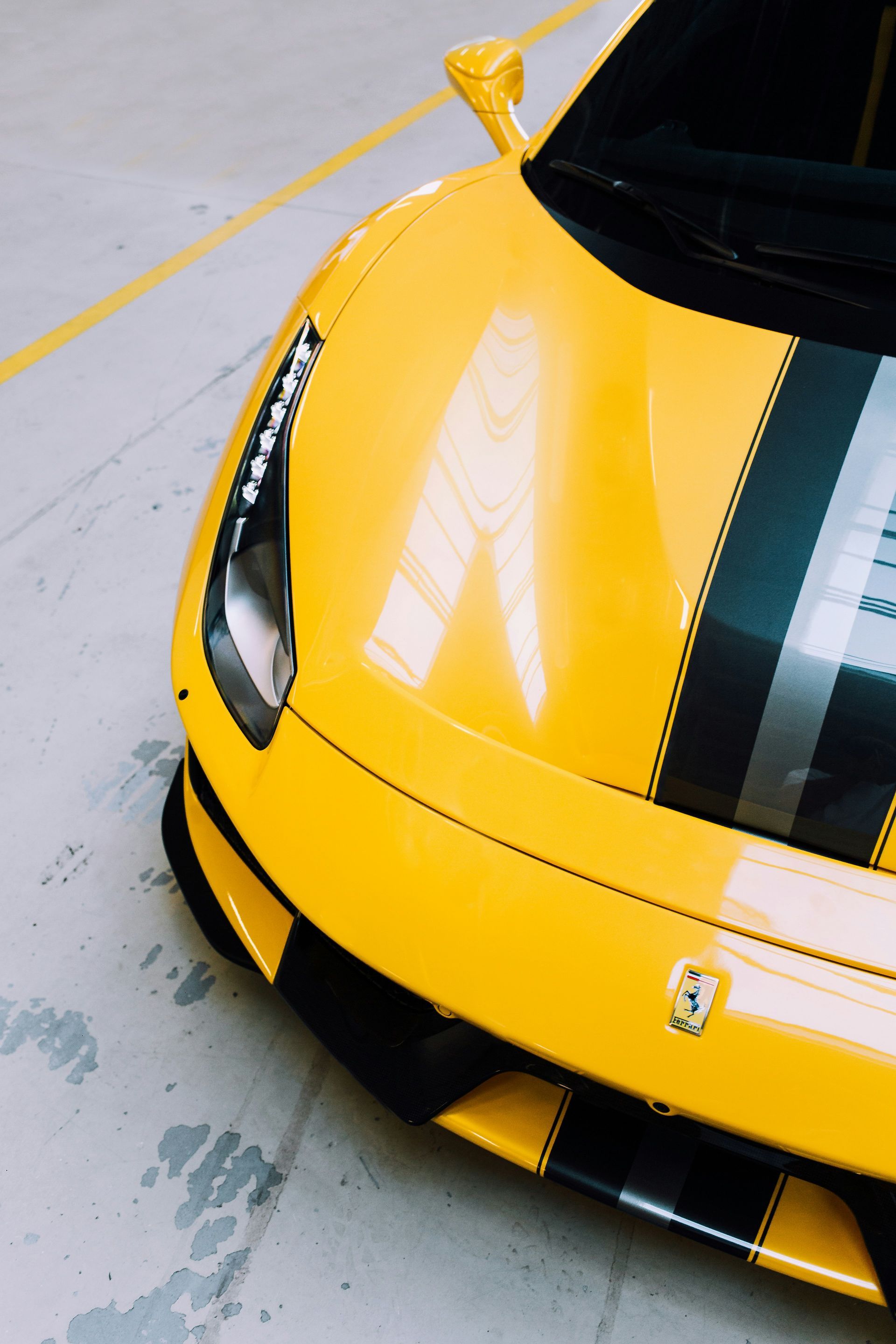 Yellow Ferrari sports car with gray racing stripes.