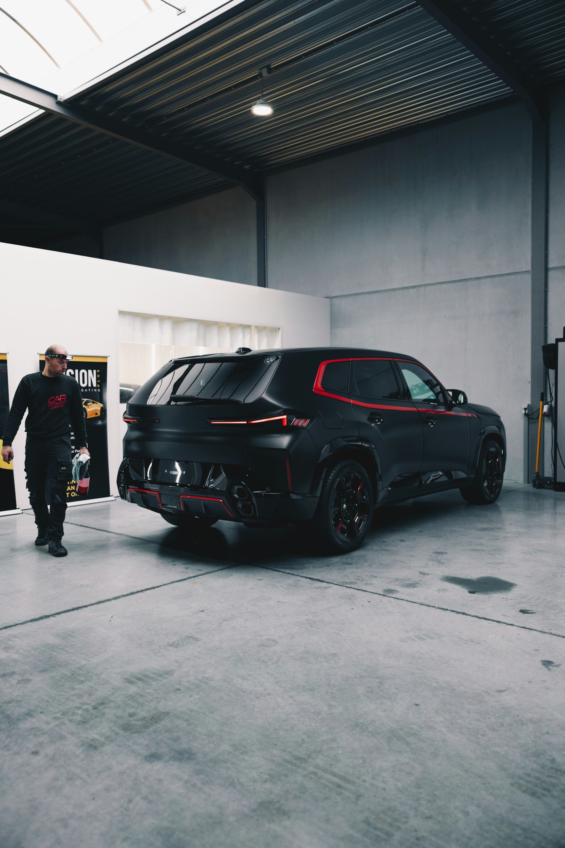 Person washing a black car with a red sponge.