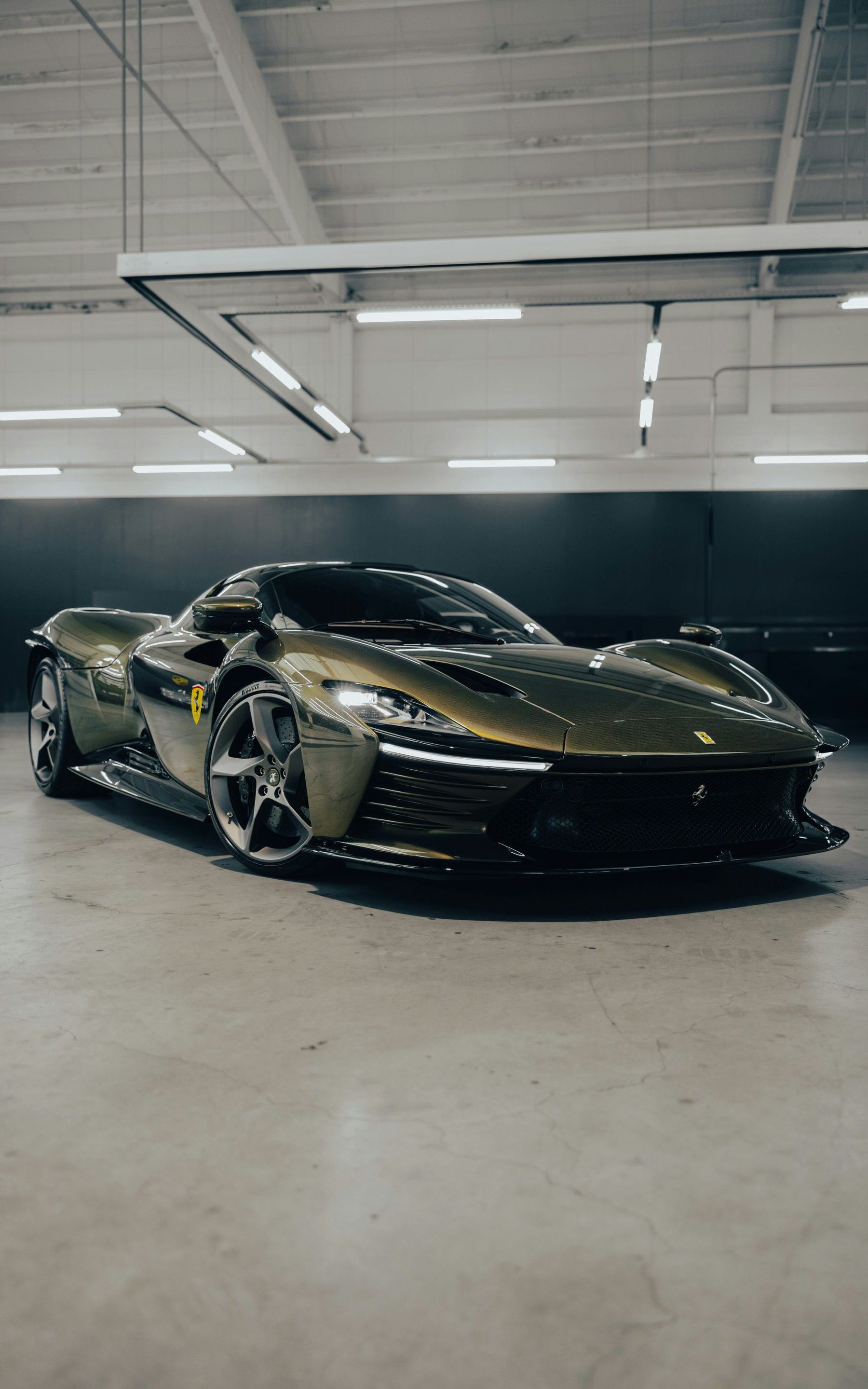 Olive green sports car parked in a garage, angled view.