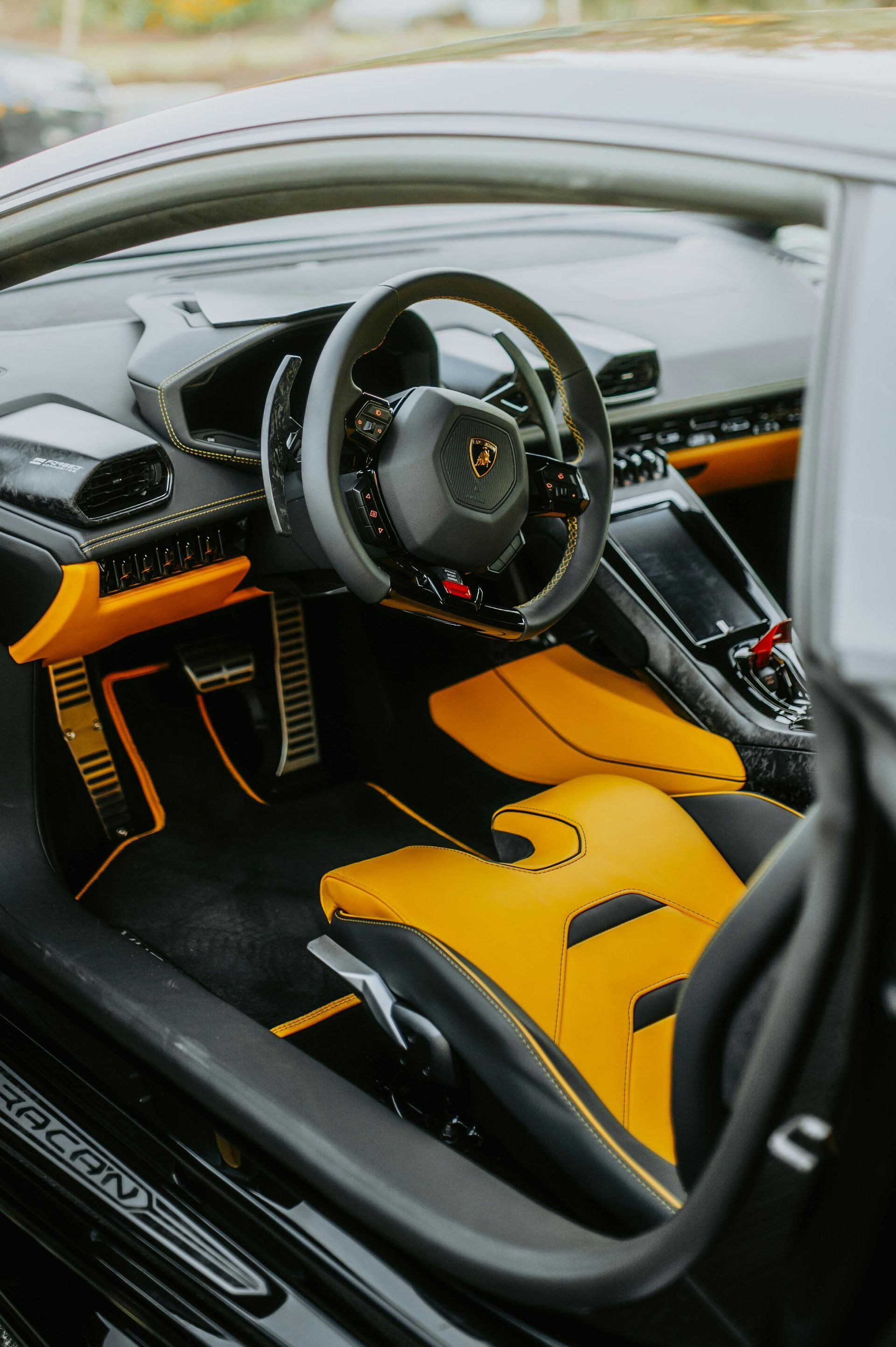 Black and yellow Lamborghini interior. Steering wheel, seats, and dashboard visible.