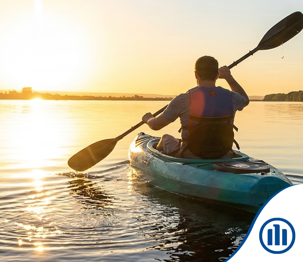 Une personne pagayant en kayak sur une étendue d'eau calme au lever du soleil, vue de dos.