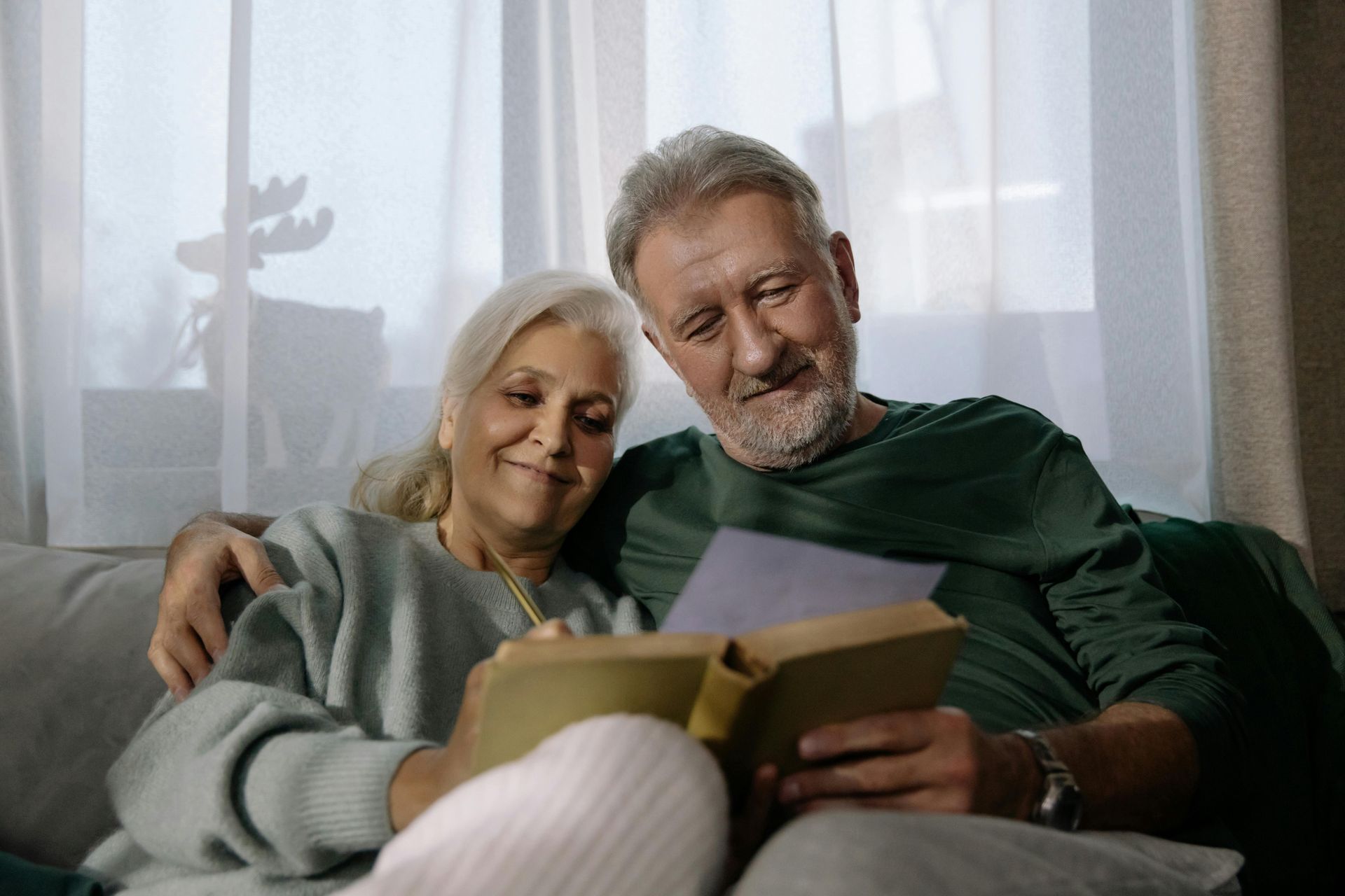 Un couple de personnes âgées, assises, regarde un livre et une photo.
