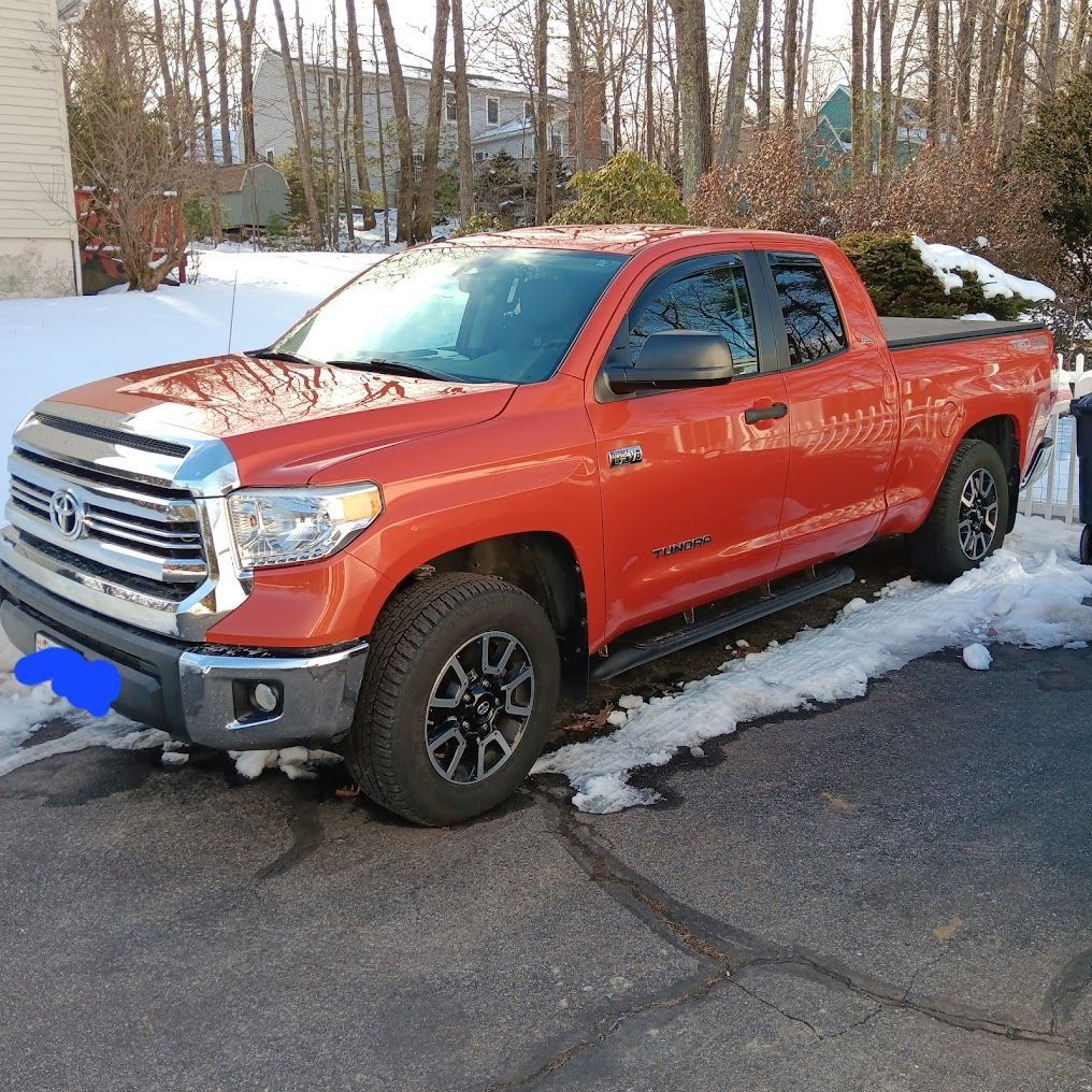 Orange pickup truck parked on a snowy driveway beside a road | Village Repair
