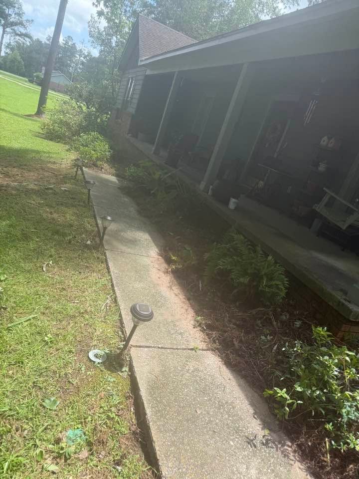 Garden path beside a house with porch and shrubs on a sunny day