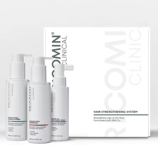 Four white hair-strengthening clinic bottles beside a white product box on a light background