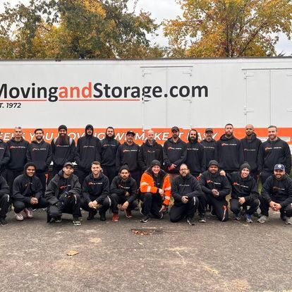 Moving crew in black uniforms in front of a white truck;