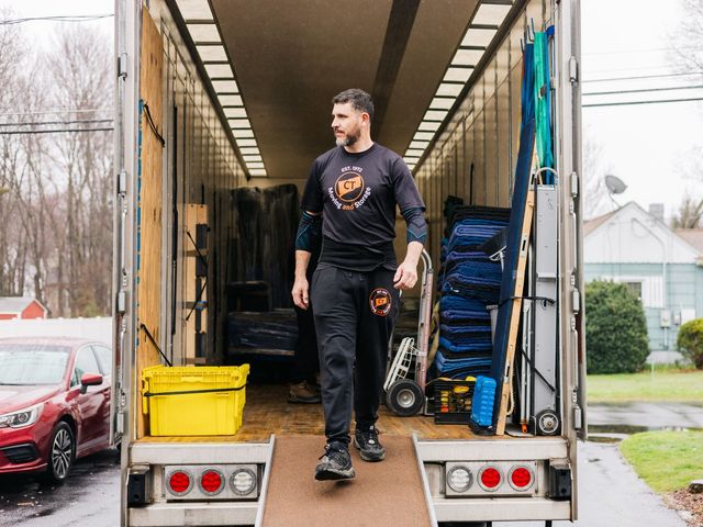 A person walks out of an open moving truck. The truck is filled with furniture and equipment.