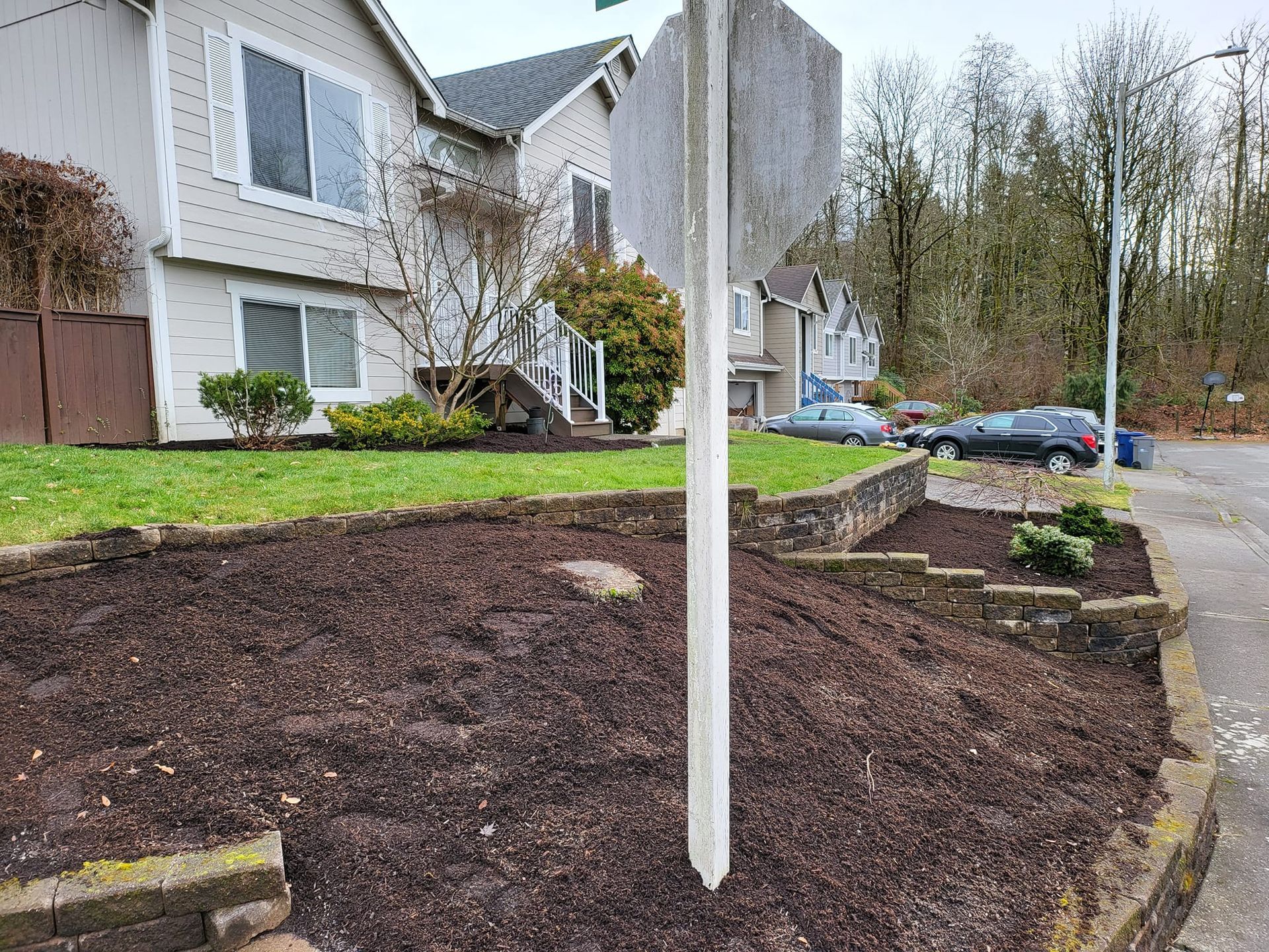 Apartment complex with a mulched garden bed and sign post in front.