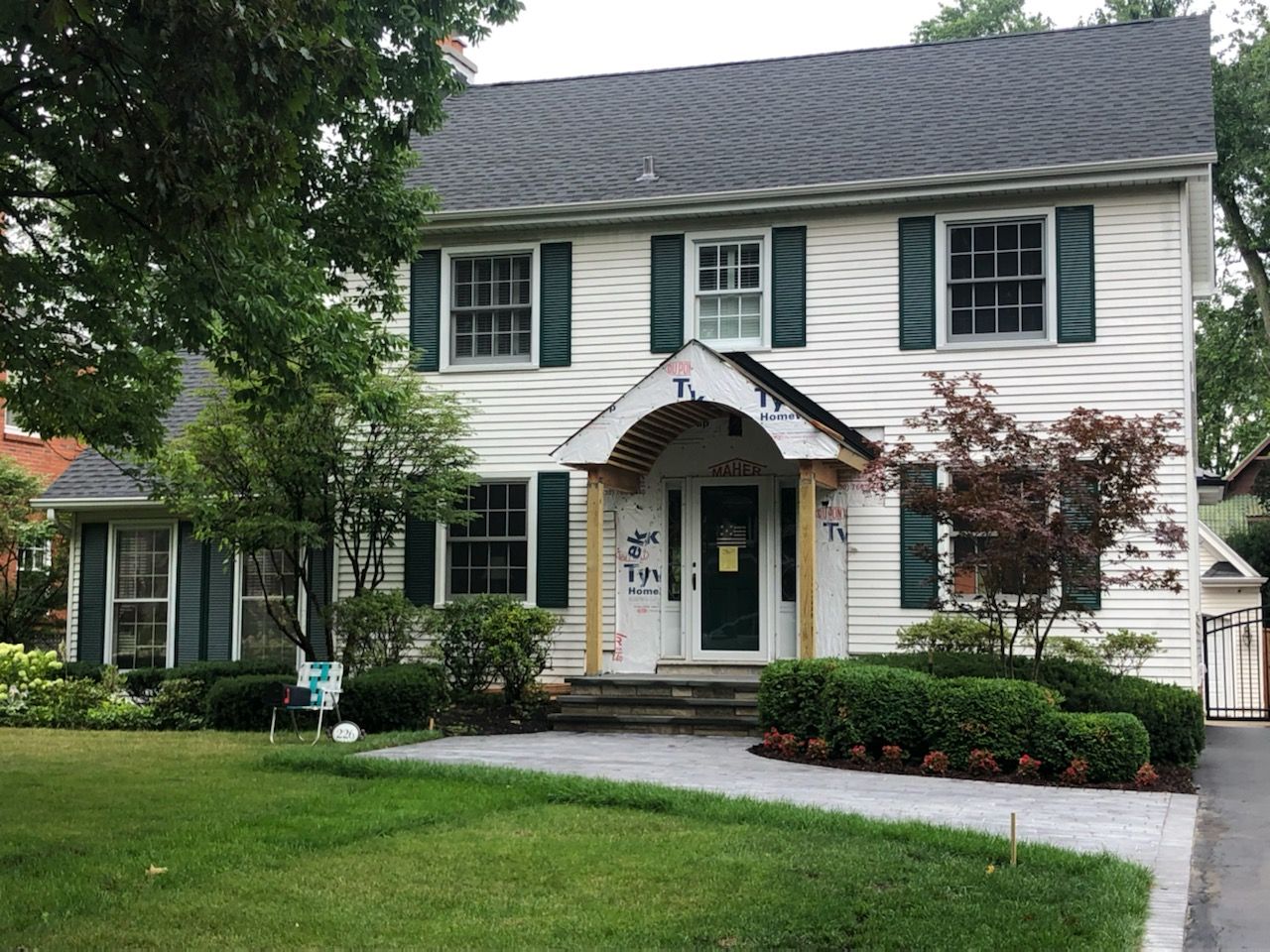 A white house with green shutters and a black roof