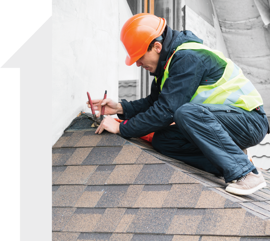 A man wearing a hard hat and safety vest is working on a roof.