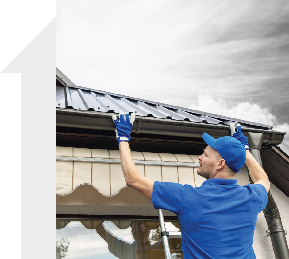 A man in a blue shirt is working on a gutter on a roof