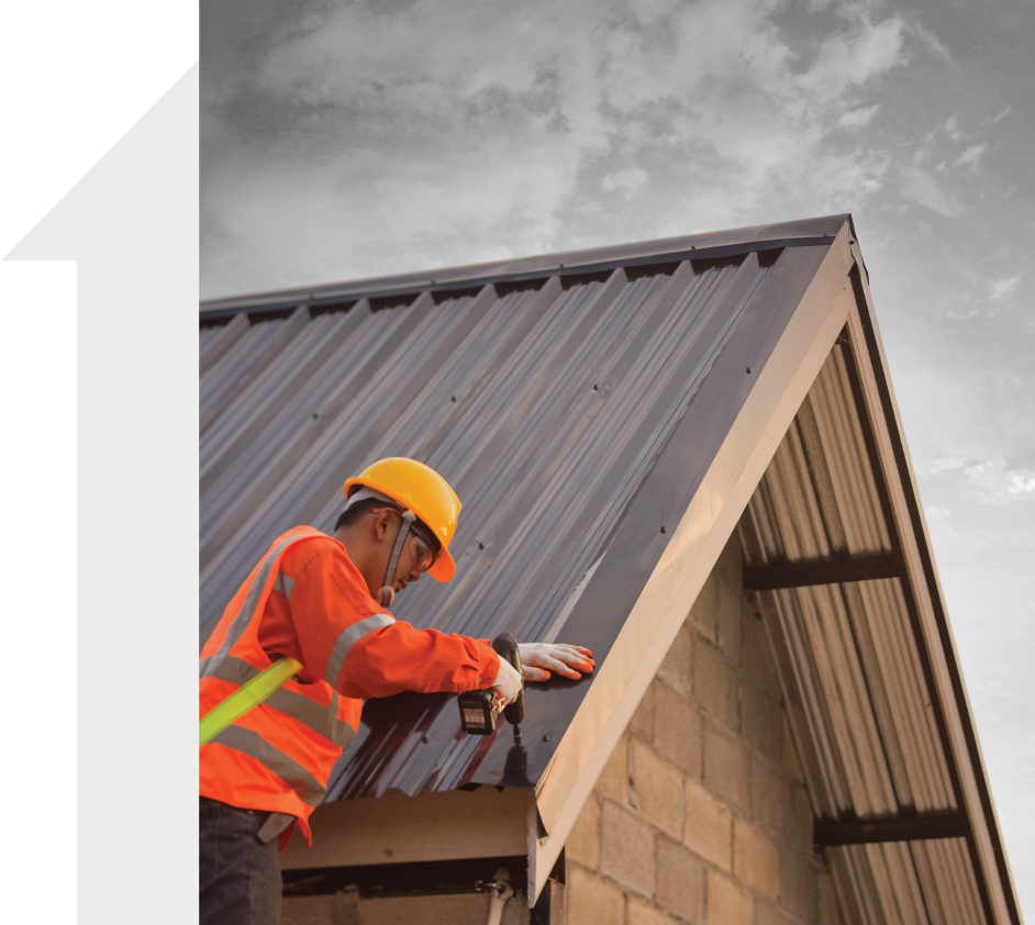 A man wearing a hard hat is working on a roof