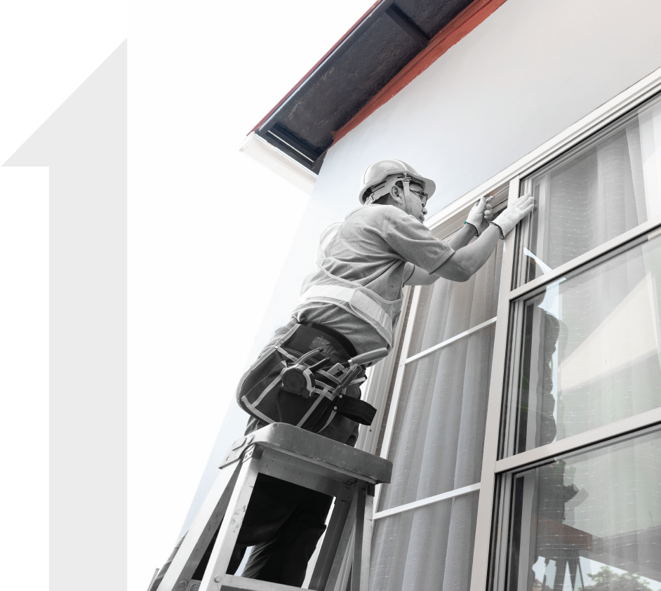 A man is standing on a ladder working on a window.