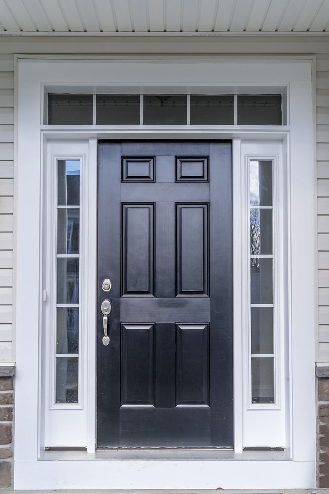 A black front door with white trim, featuring a transom window above and vertical sidelights on each side.
