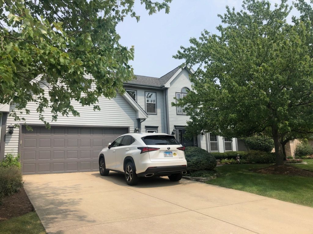 A white car is parked in front of a house.